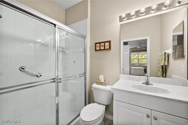 bathroom with vanity, toilet, an enclosed shower, and ceiling fan