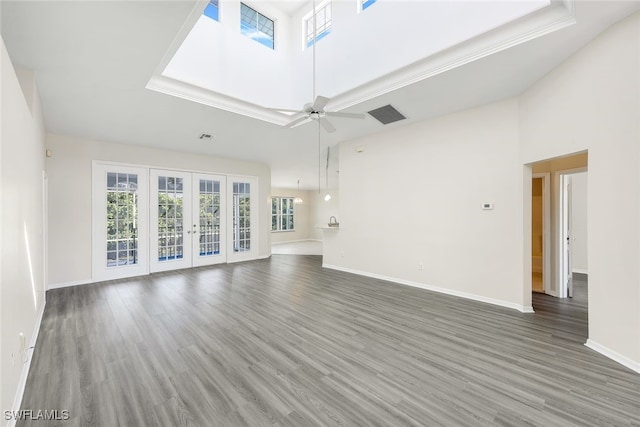 unfurnished living room with ceiling fan, a towering ceiling, french doors, dark hardwood / wood-style flooring, and a raised ceiling