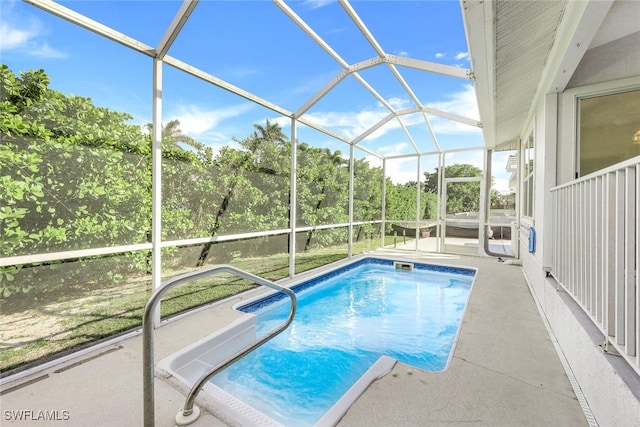 view of swimming pool featuring glass enclosure and a patio