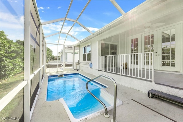 view of swimming pool with a patio area, glass enclosure, and ceiling fan