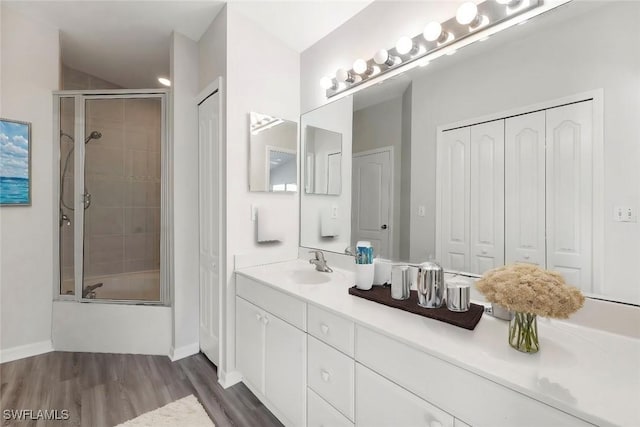 bathroom with combined bath / shower with glass door, vanity, and wood-type flooring