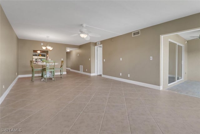 tiled spare room featuring ceiling fan with notable chandelier