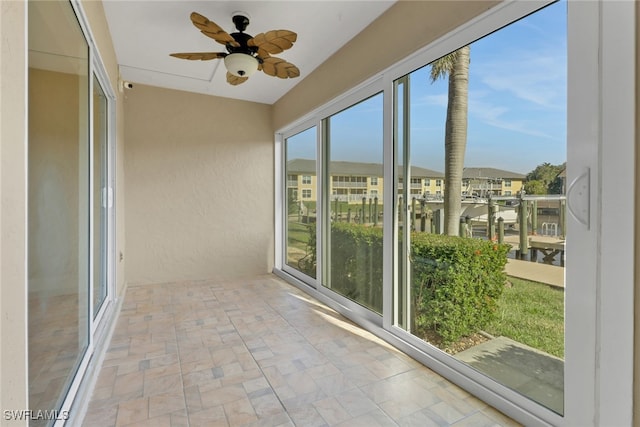 unfurnished sunroom featuring ceiling fan