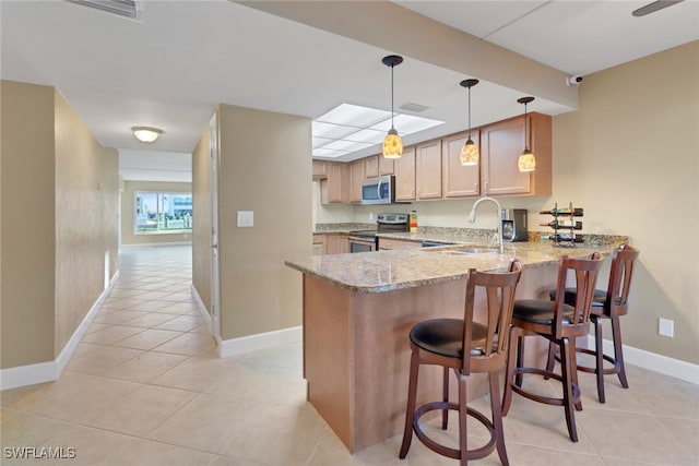 kitchen with sink, light stone counters, kitchen peninsula, light brown cabinetry, and appliances with stainless steel finishes