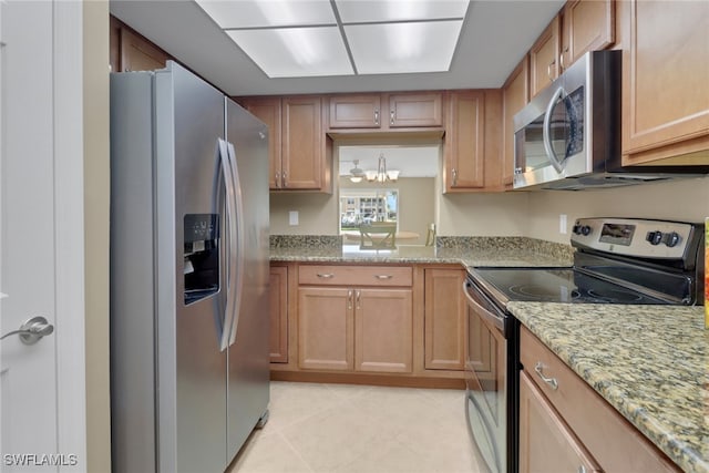 kitchen with light stone countertops, light tile patterned flooring, stainless steel appliances, and a notable chandelier