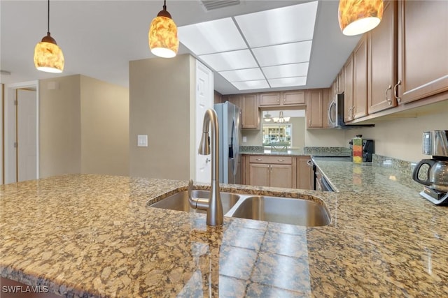 kitchen with pendant lighting, kitchen peninsula, sink, and stainless steel appliances