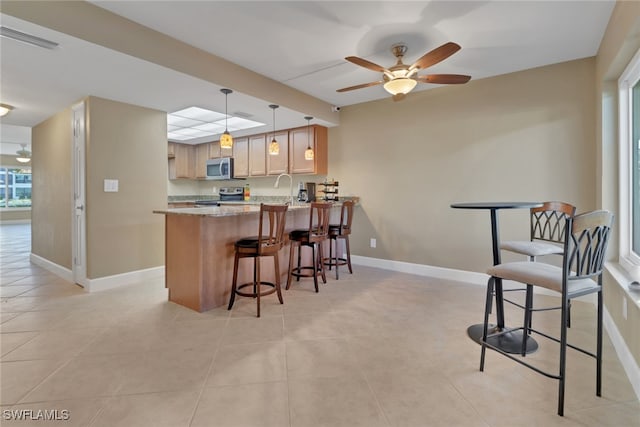 kitchen with ceiling fan, stainless steel appliances, light stone counters, kitchen peninsula, and decorative light fixtures