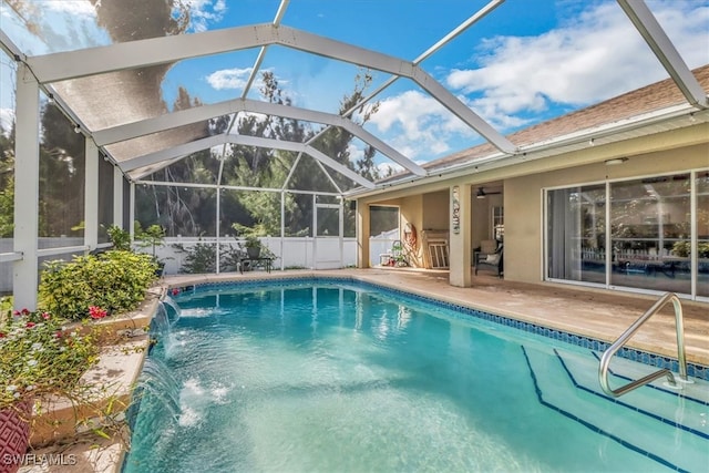 view of pool with a lanai, pool water feature, ceiling fan, and a patio