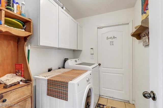 clothes washing area with separate washer and dryer, light tile patterned floors, and cabinets