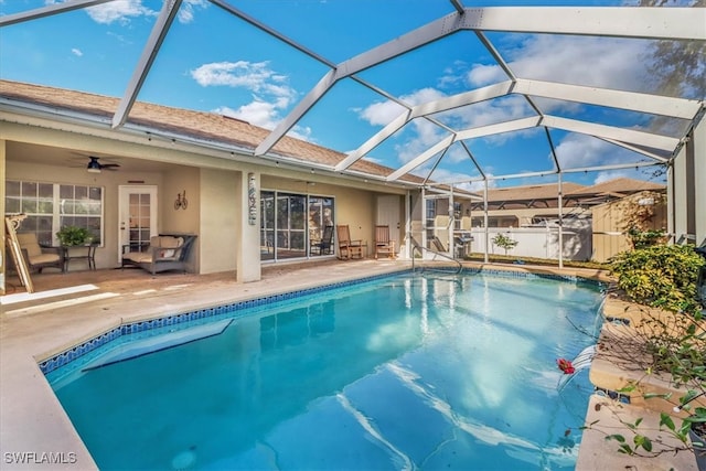 view of pool with glass enclosure, ceiling fan, and a patio area