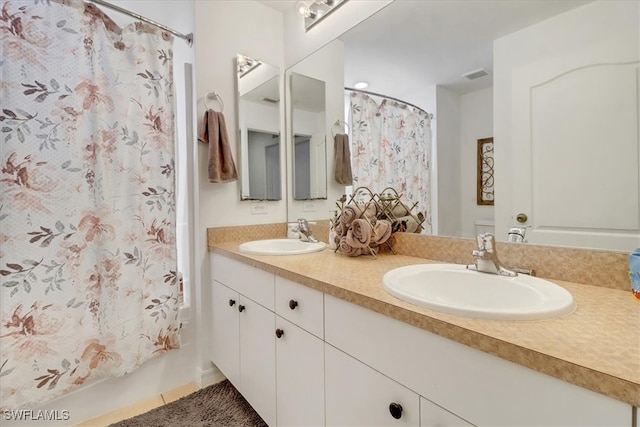 bathroom with tile patterned floors, shower / bath combo with shower curtain, and vanity