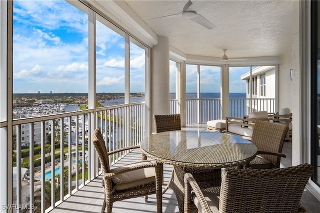 sunroom featuring a water view and a ceiling fan