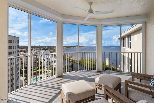 sunroom / solarium with a ceiling fan, a healthy amount of sunlight, and a water view