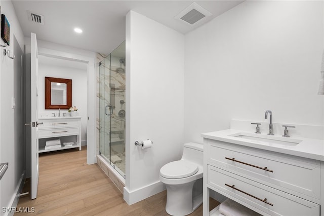 bathroom featuring a shower with door, vanity, wood-type flooring, and toilet