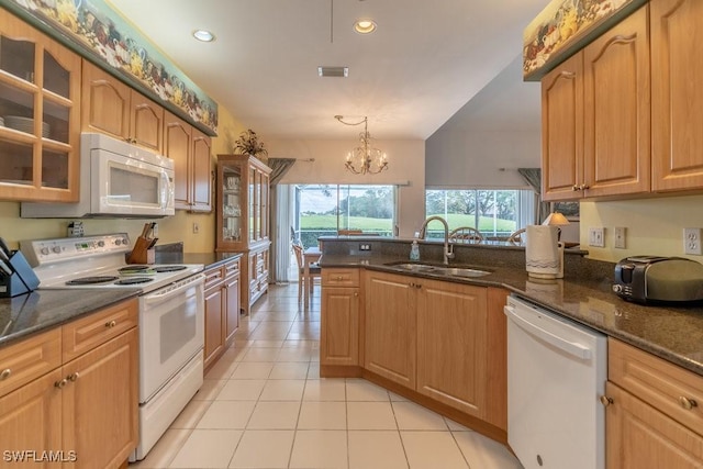 kitchen featuring white appliances, sink, decorative light fixtures, dark stone countertops, and a chandelier