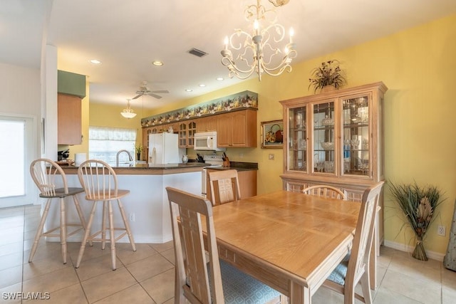 dining area featuring sink, light tile patterned floors, and ceiling fan with notable chandelier