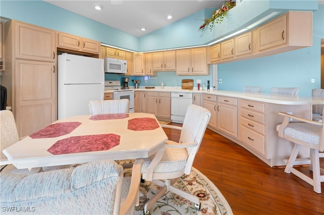 kitchen with lofted ceiling, light brown cabinets, dark wood-type flooring, and white appliances