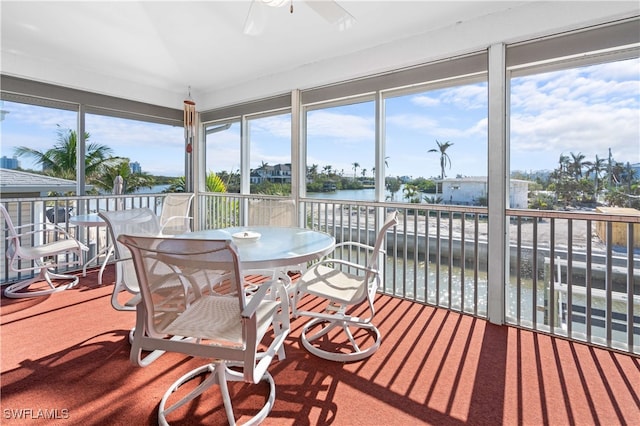 sunroom featuring ceiling fan and a water view