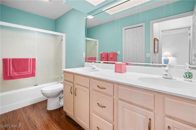 full bathroom with combined bath / shower with glass door, hardwood / wood-style floors, vanity, and toilet