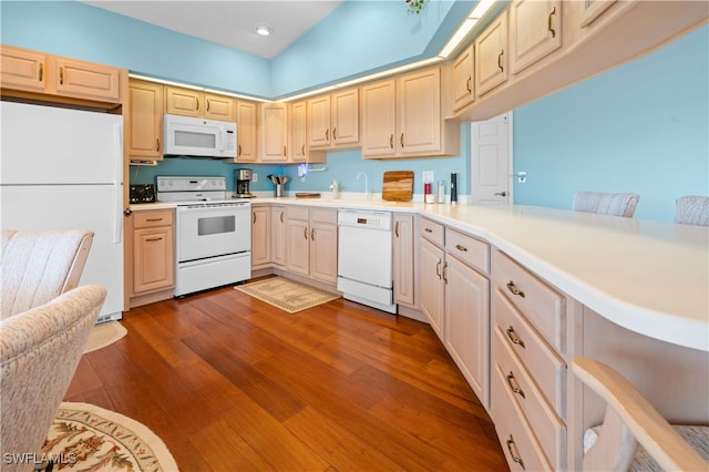 kitchen featuring kitchen peninsula, white appliances, and a breakfast bar area