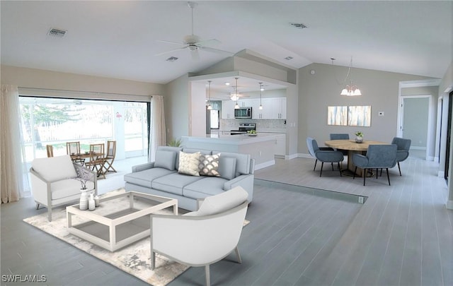 living room featuring wood-type flooring, ceiling fan with notable chandelier, and lofted ceiling