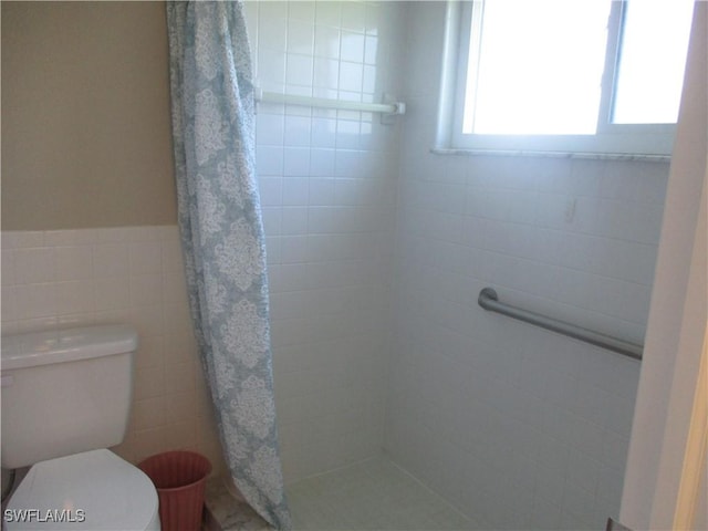 bathroom featuring a shower with curtain, toilet, and tile walls