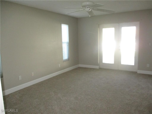 carpeted spare room with ceiling fan and french doors