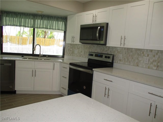 kitchen featuring light stone countertops, sink, decorative backsplash, white cabinets, and appliances with stainless steel finishes