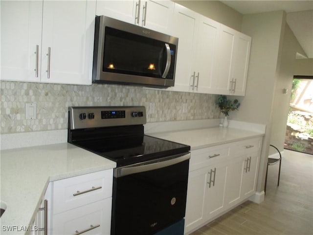 kitchen with backsplash, white cabinets, light wood-type flooring, appliances with stainless steel finishes, and light stone counters