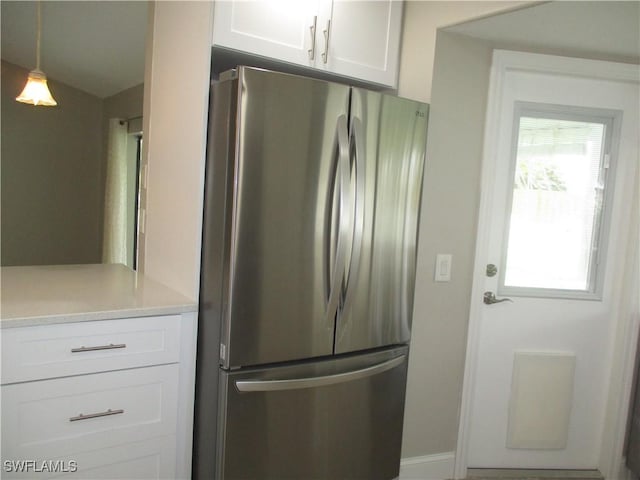 kitchen with white cabinets, stainless steel fridge, vaulted ceiling, and pendant lighting