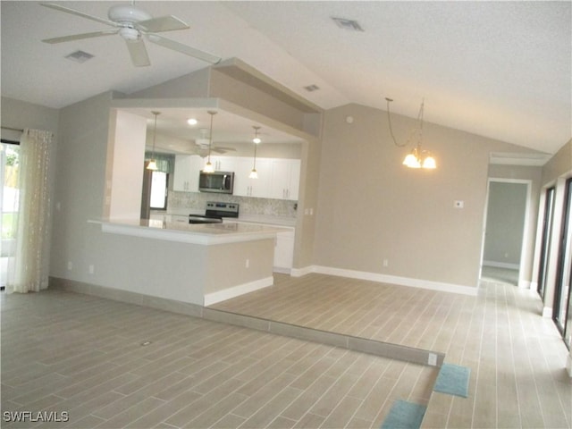 kitchen featuring white cabinetry, stainless steel appliances, tasteful backsplash, vaulted ceiling, and decorative light fixtures