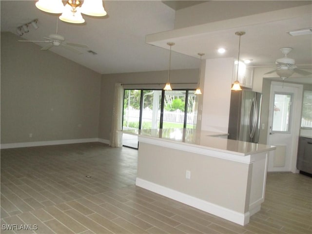 kitchen featuring stainless steel fridge, white cabinets, pendant lighting, and vaulted ceiling