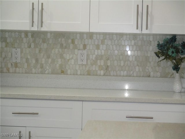 details featuring light stone counters, white cabinetry, and backsplash