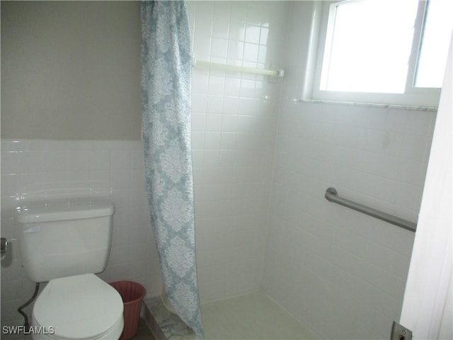 bathroom featuring toilet, tile walls, and curtained shower