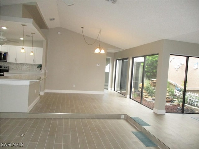 kitchen featuring hanging light fixtures, an inviting chandelier, backsplash, vaulted ceiling, and white cabinets