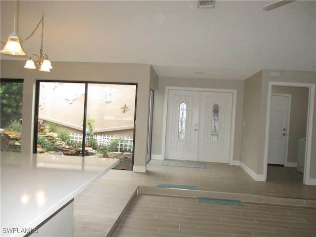 foyer entrance with hardwood / wood-style floors and an inviting chandelier