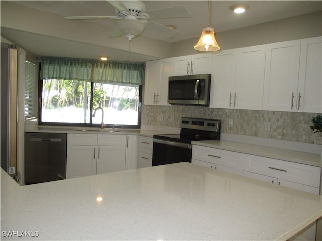 kitchen with white cabinets, hanging light fixtures, sink, appliances with stainless steel finishes, and light stone counters