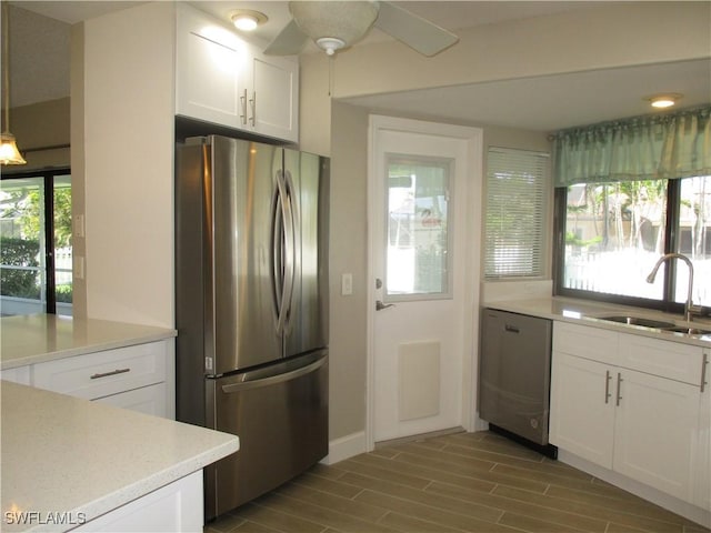 kitchen featuring appliances with stainless steel finishes, sink, pendant lighting, hardwood / wood-style floors, and white cabinetry