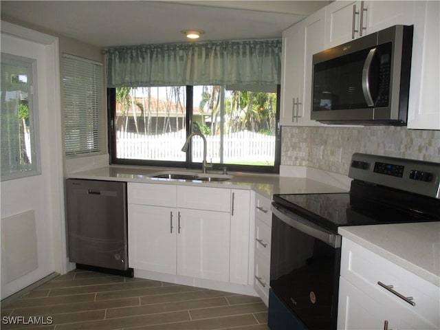 kitchen featuring decorative backsplash, appliances with stainless steel finishes, white cabinetry, and sink