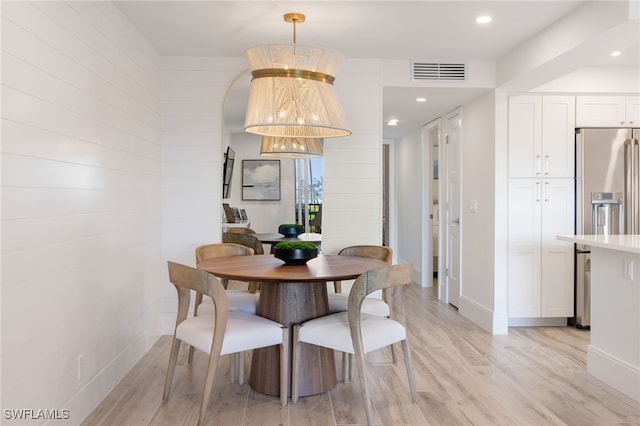 dining area with light hardwood / wood-style floors and a notable chandelier