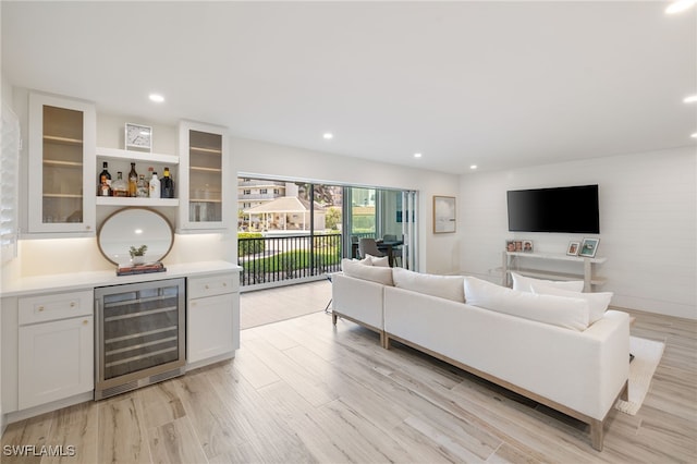 living room featuring bar, beverage cooler, and light wood-type flooring