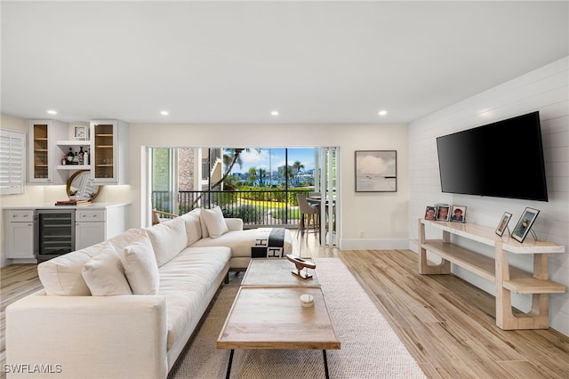 living room featuring light wood-type flooring, beverage cooler, and indoor bar