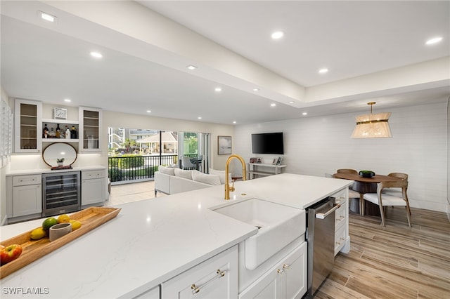 kitchen featuring dishwasher, sink, wine cooler, light stone countertops, and decorative light fixtures