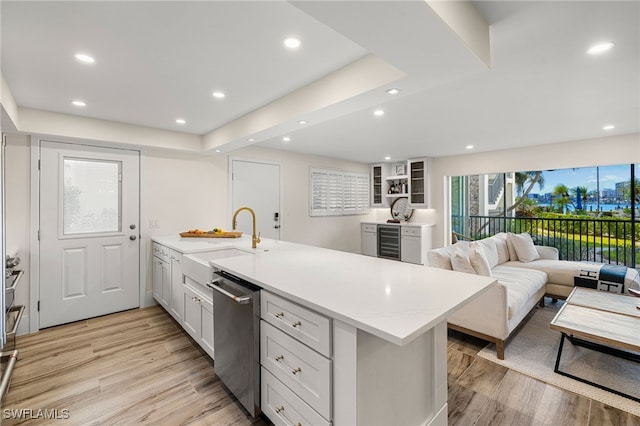 kitchen with stainless steel dishwasher, sink, beverage cooler, and light hardwood / wood-style flooring