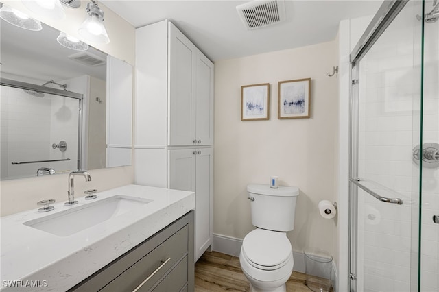 bathroom with walk in shower, hardwood / wood-style floors, vanity, and toilet