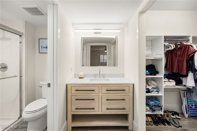 bathroom featuring hardwood / wood-style flooring, a shower with door, vanity, and toilet