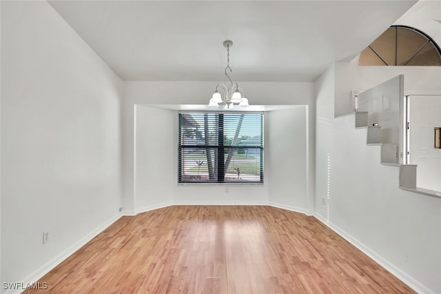 empty room featuring an inviting chandelier and hardwood / wood-style floors