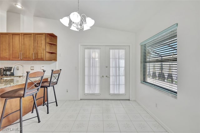 interior space featuring sink, a breakfast bar, light stone countertops, vaulted ceiling, and french doors