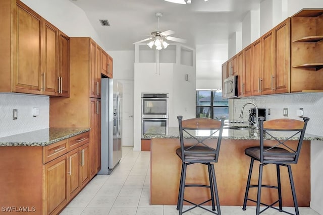 kitchen with dark stone countertops, sink, a breakfast bar area, and appliances with stainless steel finishes