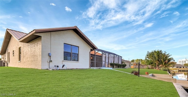 rear view of house featuring cooling unit, glass enclosure, and a lawn